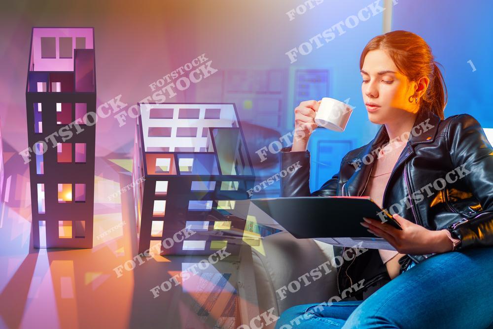 На фотографии изображена молодая женщина, работающая с планшетом и наслаждающаяся чашкой кофе. На переднем плане представлены макеты зданий, символизирующие архитектурное проектирование. Снимок подчёркивает творческий процесс и использование современных технологий в архитектуре.